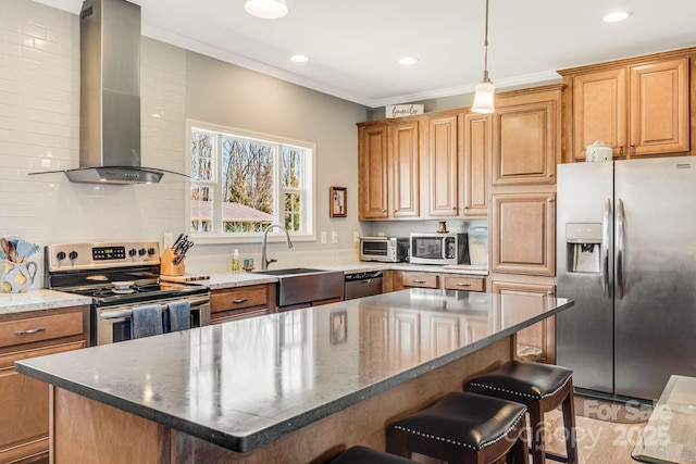 kitchen featuring ornamental molding, a sink, appliances with stainless steel finishes, a kitchen bar, and wall chimney range hood