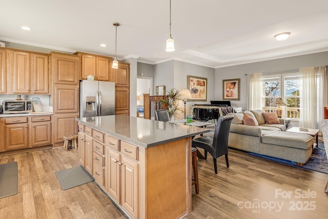 kitchen featuring stainless steel fridge, light wood-style floors, a center island, and crown molding