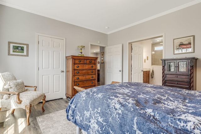 bedroom featuring connected bathroom, light wood-type flooring, and ornamental molding