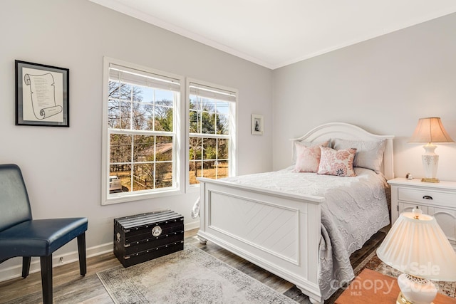 bedroom featuring ornamental molding, baseboards, and wood finished floors