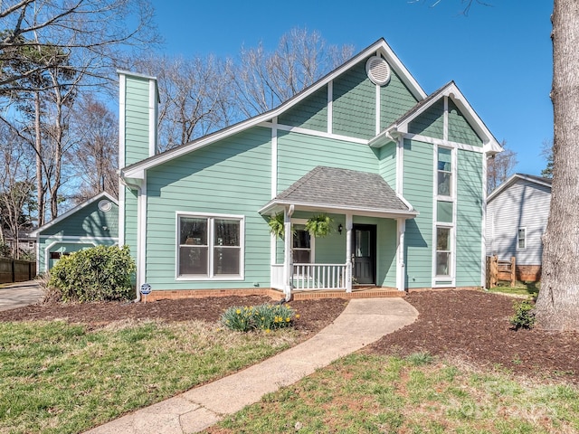 view of front of house featuring covered porch, a chimney, and a shingled roof