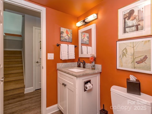 bathroom featuring toilet, vanity, baseboards, and wood finished floors