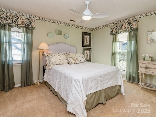 bedroom featuring a ceiling fan, multiple windows, light colored carpet, and visible vents