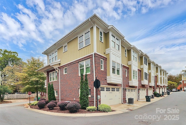 view of building exterior featuring a residential view, central AC unit, and an attached garage