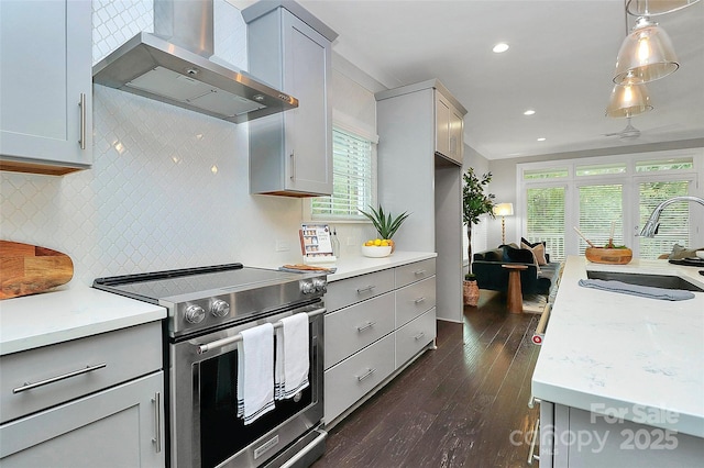 kitchen with a sink, wall chimney range hood, gray cabinets, and stainless steel range with electric cooktop