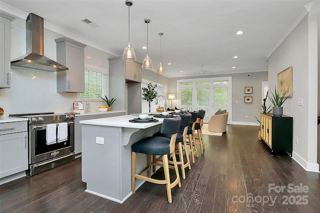 kitchen with stainless steel range with electric stovetop, gray cabinetry, tasteful backsplash, wall chimney exhaust hood, and light countertops