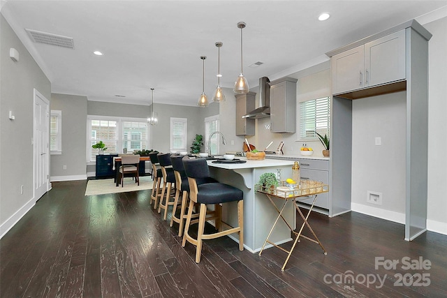 kitchen with visible vents, dark wood finished floors, light countertops, gray cabinets, and wall chimney exhaust hood