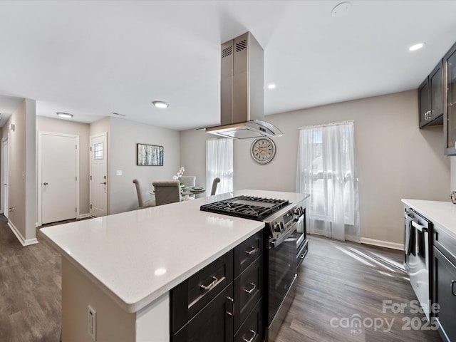 kitchen featuring island exhaust hood, stainless steel gas stove, dark wood finished floors, and light countertops