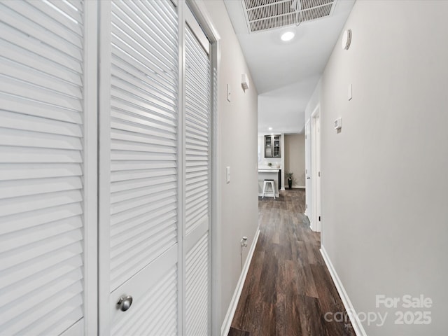 hall featuring dark wood finished floors, baseboards, and visible vents