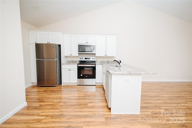 kitchen featuring light stone countertops, appliances with stainless steel finishes, a peninsula, white cabinets, and a sink