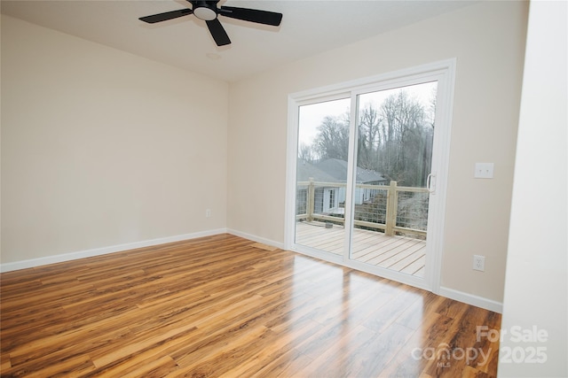 empty room with a ceiling fan, baseboards, and wood finished floors