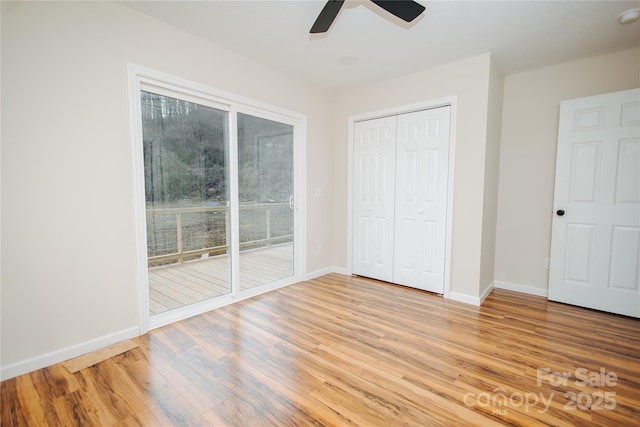 unfurnished bedroom featuring access to exterior, a closet, baseboards, and wood finished floors