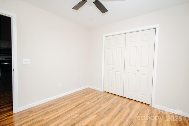 unfurnished bedroom with light wood-type flooring, baseboards, a closet, and ceiling fan