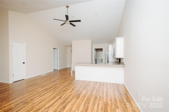 unfurnished living room featuring baseboards, ceiling fan, high vaulted ceiling, and light wood-style floors