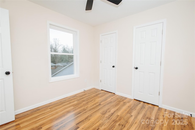 unfurnished bedroom with a ceiling fan, wood finished floors, and baseboards