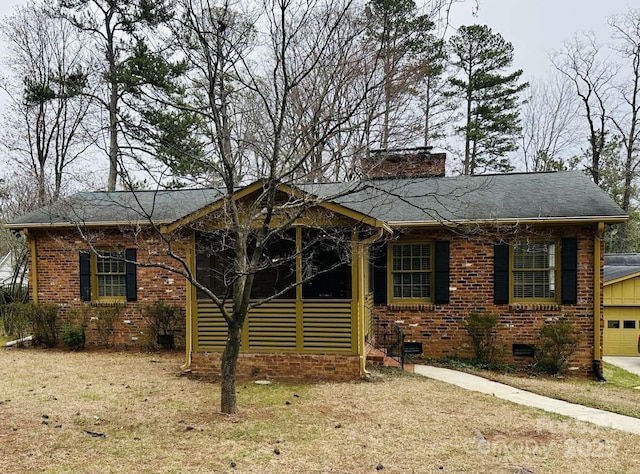 view of front facade with brick siding, a front lawn, a chimney, a garage, and crawl space