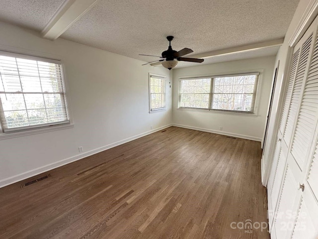 unfurnished bedroom with wood finished floors, baseboards, visible vents, a closet, and a textured ceiling