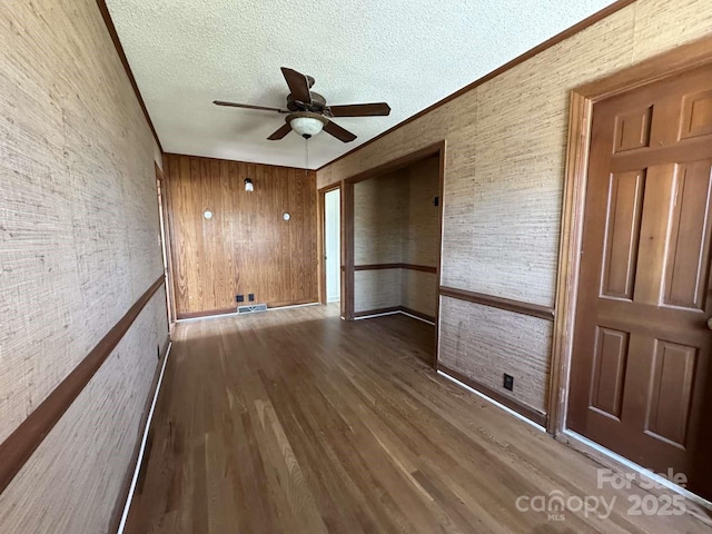 empty room featuring ceiling fan, a textured ceiling, wood finished floors, and crown molding