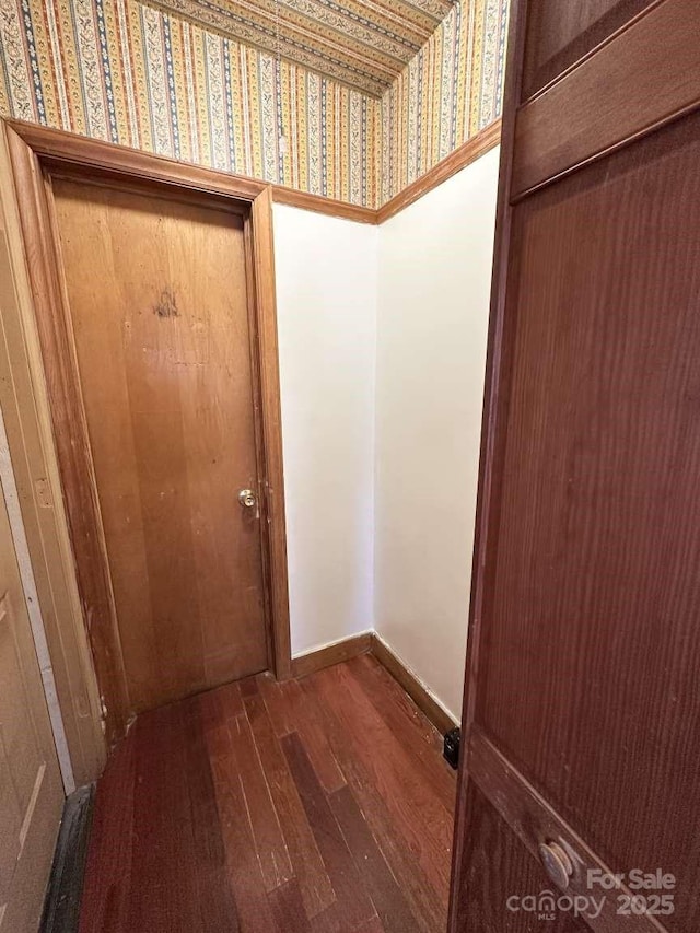 doorway to outside featuring wallpapered walls, baseboards, and hardwood / wood-style floors