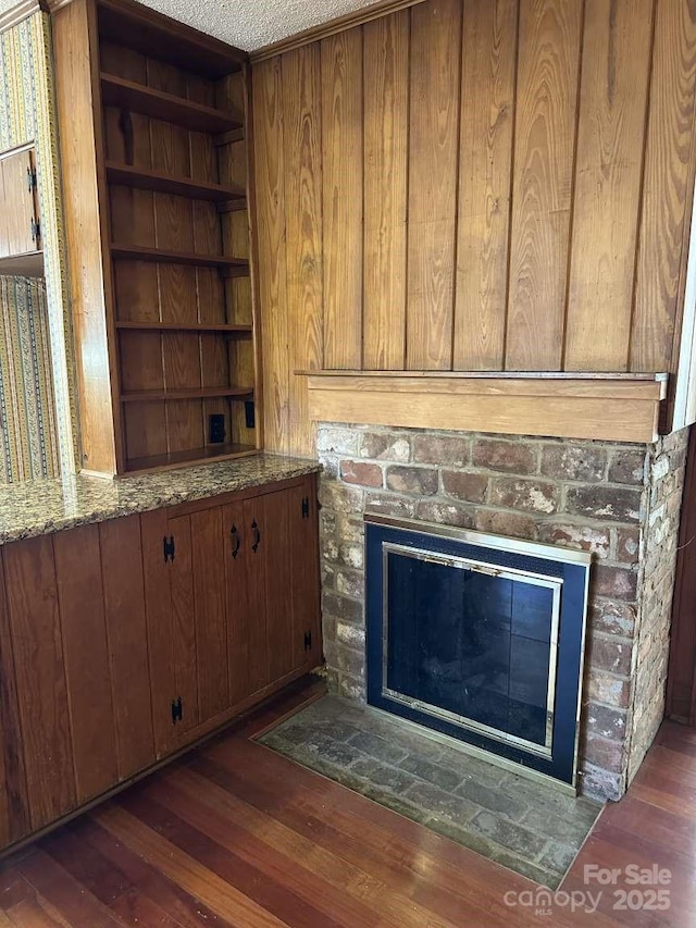 details with a glass covered fireplace, built in features, wood finished floors, and a textured ceiling