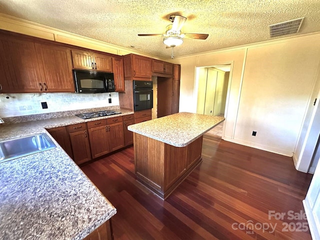 kitchen with dark wood-style floors, visible vents, a kitchen island, a sink, and black appliances