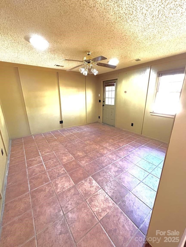 spare room with a textured ceiling and a ceiling fan