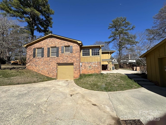 exterior space with a garage, brick siding, concrete driveway, and a front yard