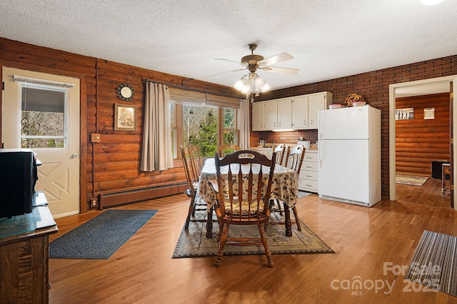 dining space with a baseboard heating unit, ceiling fan, light wood-style floors, a textured ceiling, and log walls