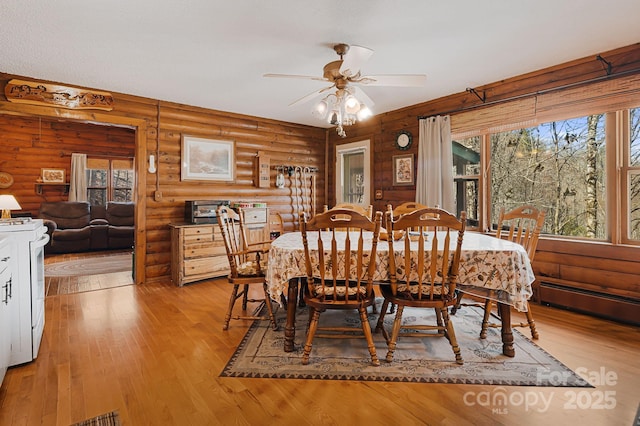 dining room with light wood-style flooring, log walls, and ceiling fan