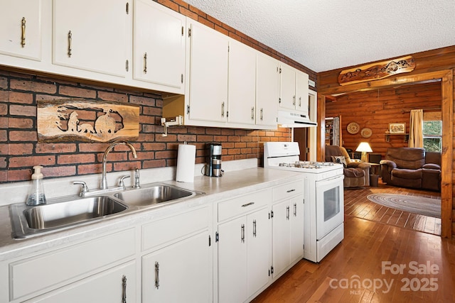 kitchen featuring light wood-style flooring, a sink, under cabinet range hood, a textured ceiling, and white gas range oven