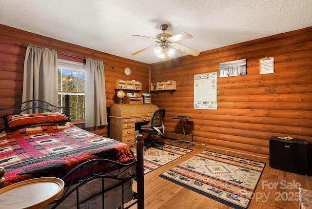 bedroom featuring log walls, wood-type flooring, and a textured ceiling