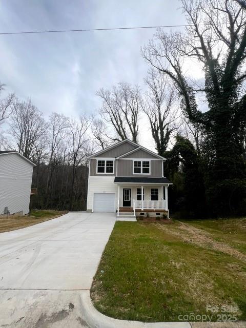 view of front facade featuring a front yard, an attached garage, covered porch, and driveway