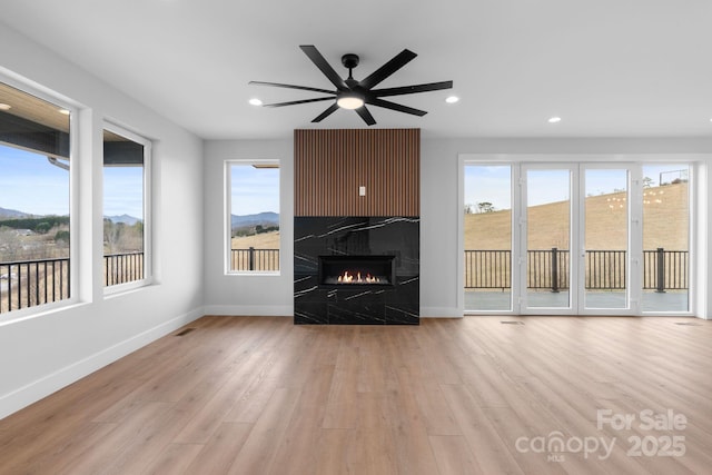 unfurnished living room featuring baseboards, a healthy amount of sunlight, wood finished floors, and a fireplace