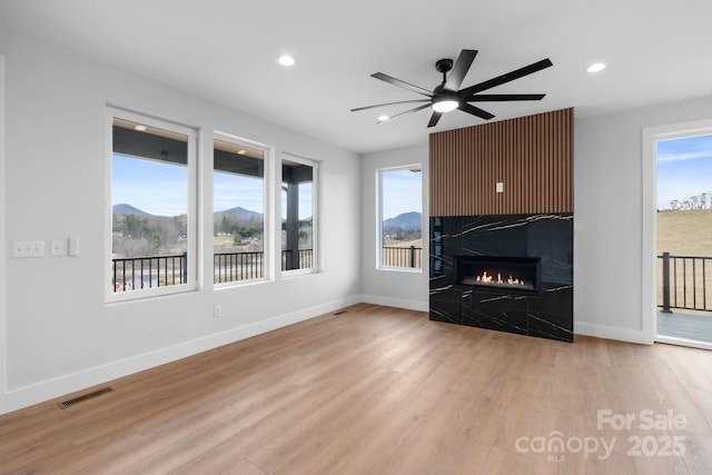 unfurnished living room featuring visible vents, light wood-style flooring, a fireplace, and baseboards