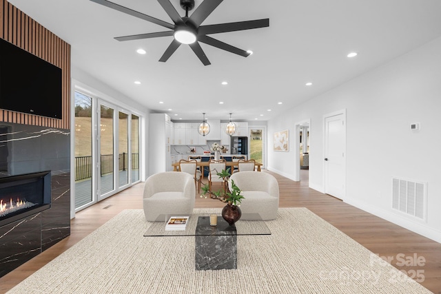 living room featuring a wealth of natural light, visible vents, recessed lighting, and a tiled fireplace