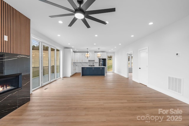 unfurnished living room with visible vents, baseboards, recessed lighting, light wood-style flooring, and a fireplace