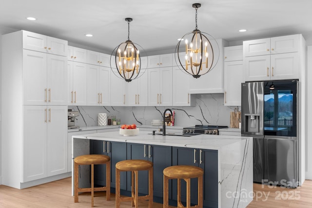 kitchen with a sink, appliances with stainless steel finishes, white cabinets, and hanging light fixtures