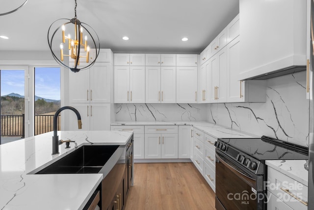 kitchen with a sink, pendant lighting, white cabinetry, and black electric range