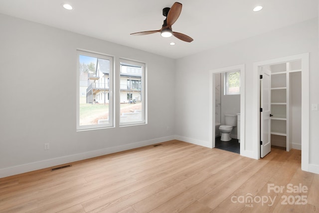 unfurnished bedroom featuring baseboards, visible vents, light wood finished floors, recessed lighting, and a walk in closet