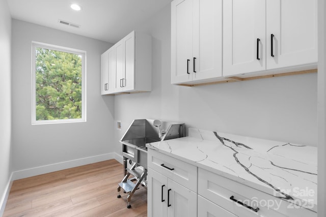 office space featuring a wealth of natural light, visible vents, light wood finished floors, and baseboards