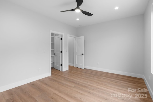 unfurnished bedroom with a spacious closet, baseboards, recessed lighting, light wood-style floors, and a ceiling fan