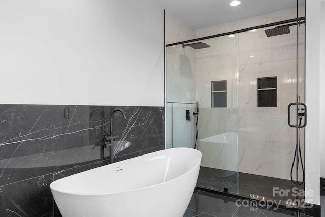 bathroom featuring tile walls, recessed lighting, a marble finish shower, and a freestanding bath