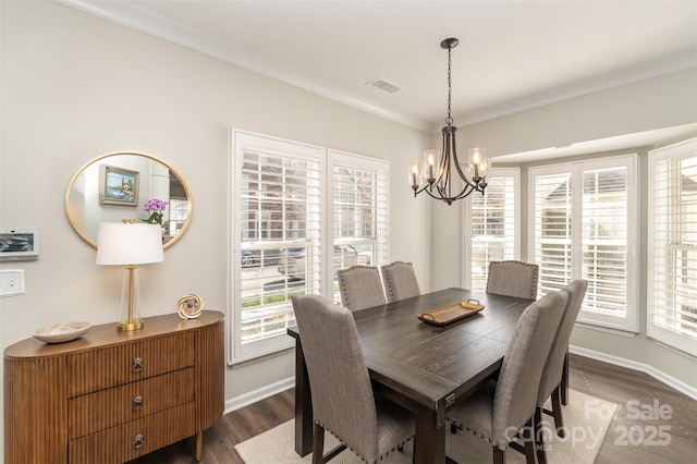 dining area with dark wood finished floors, crown molding, baseboards, and a chandelier