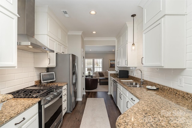 kitchen with white cabinets, wall chimney exhaust hood, appliances with stainless steel finishes, and a sink