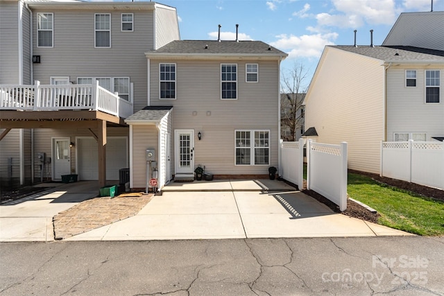 back of house featuring a garage, concrete driveway, and fence