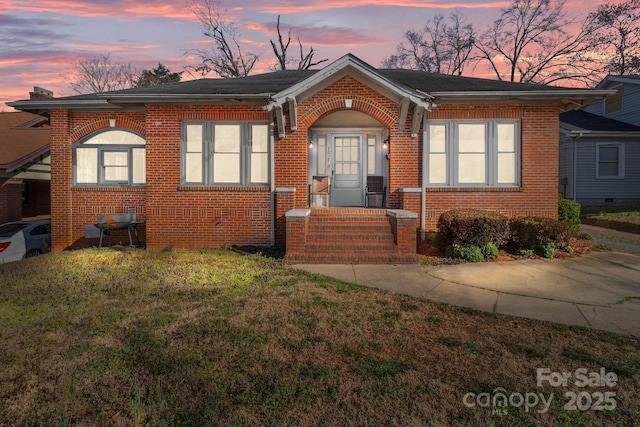 bungalow-style house with brick siding and a front yard