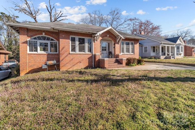 bungalow-style house featuring a front yard and brick siding