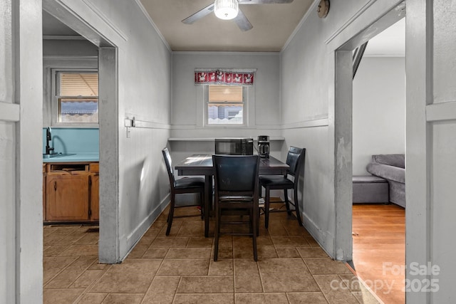 tiled dining space with arched walkways, baseboards, crown molding, and ceiling fan