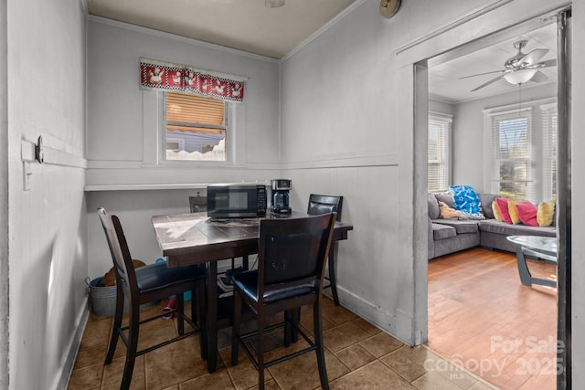 dining area with baseboards, ceiling fan, and crown molding