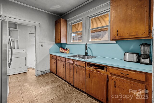 kitchen featuring brown cabinetry, washer / dryer, light countertops, and a sink